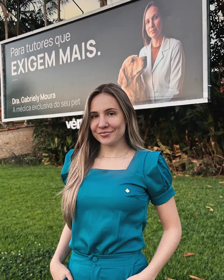 Dra. Gabriely Moura, com o outdoor da marca ao fundo